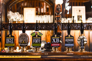 Row of Theakston beer taps with various labels on a bar counter.